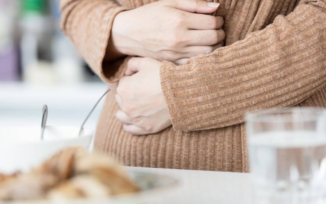 Frau greift sich auf ihren schmerzenden Bauch und kann ihre Symptome nur erahnen.